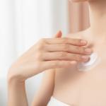 Dekolleté pflegen und straffen für Eleganz und Weiblichkeit Frau trägt sanft Creme auf ihr gepflegtes Dekolleté auf, Hautpflege-Routine